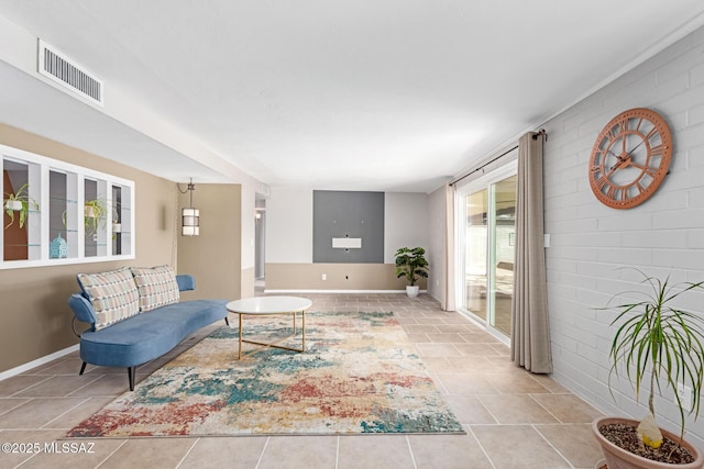 living area featuring visible vents, baseboards, and brick wall