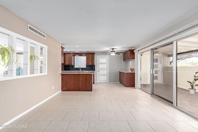 kitchen with a ceiling fan, visible vents, a peninsula, a sink, and light countertops