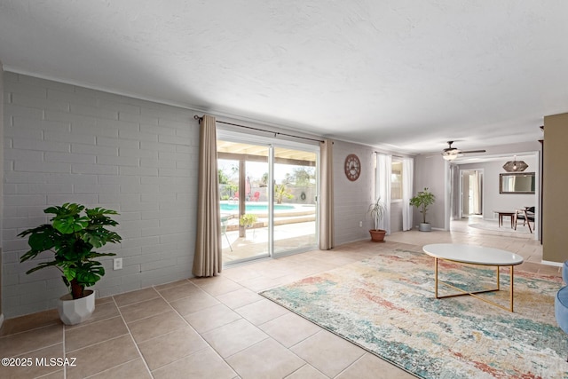 tiled living area with brick wall, a textured ceiling, and a ceiling fan