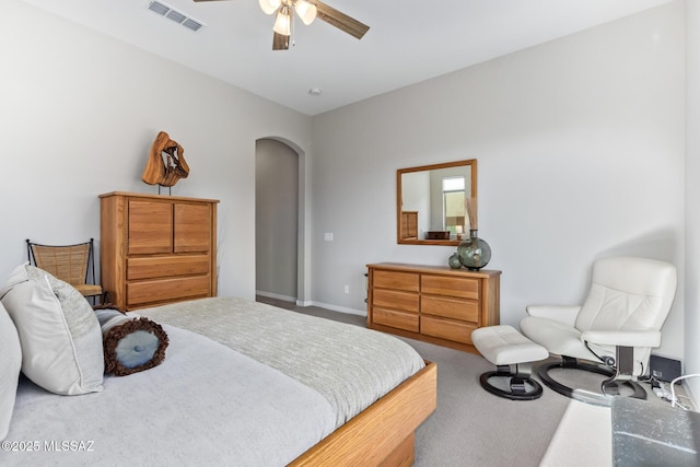 carpeted bedroom featuring arched walkways, visible vents, a ceiling fan, and baseboards