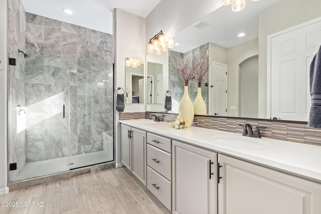 full bathroom featuring a sink, visible vents, double vanity, and a shower stall