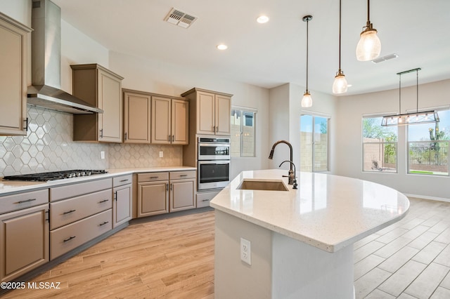 6909 W Cliff Spring Trl, Marana, AZ 85658 - kitchen featuring wall chimney exhaust hood, a sink, light wood-type flooring, an island with sink, and backsplash