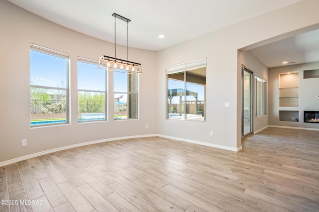 6909 W Cliff Spring Trl, Marana, AZ 85658 - spare room with plenty of natural light, built in shelves, light wood-style floors, baseboards, and recessed lighting