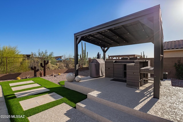 exterior space with a fenced backyard, a grill, and outdoor dry bar