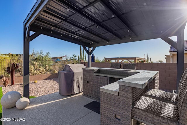 view of patio with an outdoor kitchen, a grill, a fenced backyard, and outdoor dry bar