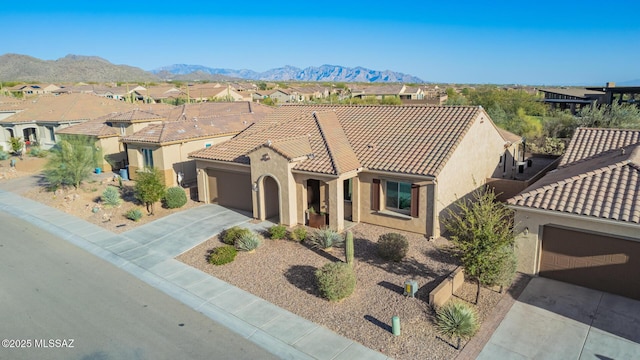 mediterranean / spanish house with a residential view, concrete driveway, a garage, a tile roof, and a mountain view