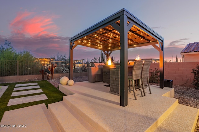 6909 W Cliff Spring Trl, Marana, AZ 85658 - patio terrace at dusk with a gazebo, a fire pit, a patio area, and area for grilling