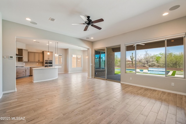 6909 W Cliff Spring Trl, Marana, AZ 85658 - unfurnished living room with light wood-type flooring, ceiling fan, baseboards, and recessed lighting