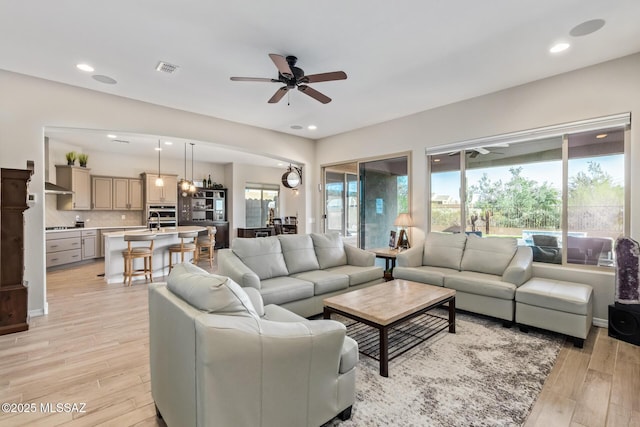 living area with light wood finished floors, a healthy amount of sunlight, and a ceiling fan