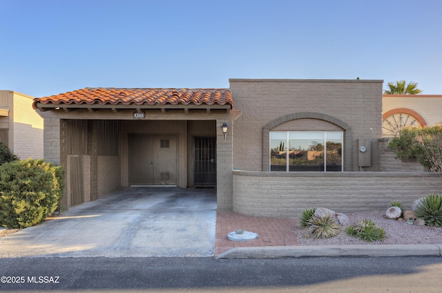 view of front of property with brick siding, an attached carport, a tiled roof, and concrete driveway