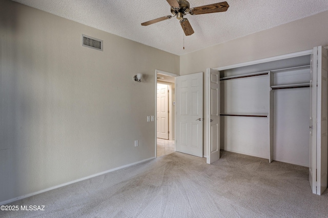 unfurnished bedroom with visible vents, ceiling fan, carpet flooring, a closet, and a textured ceiling