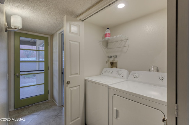 clothes washing area featuring washer and dryer, a textured ceiling, laundry area, and light tile patterned floors