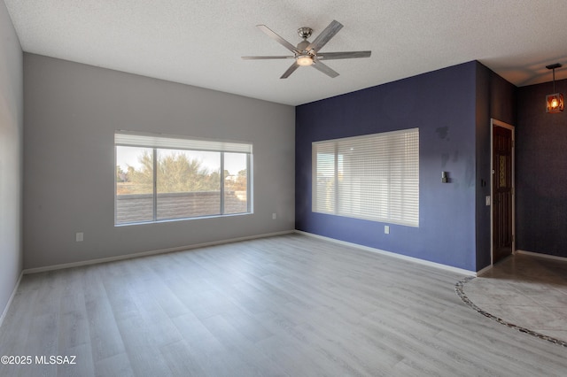 unfurnished room with ceiling fan, a textured ceiling, baseboards, and wood finished floors