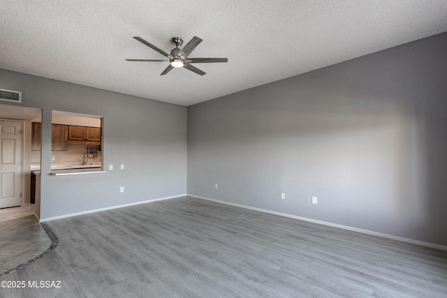 empty room with baseboards, wood finished floors, visible vents, and ceiling fan