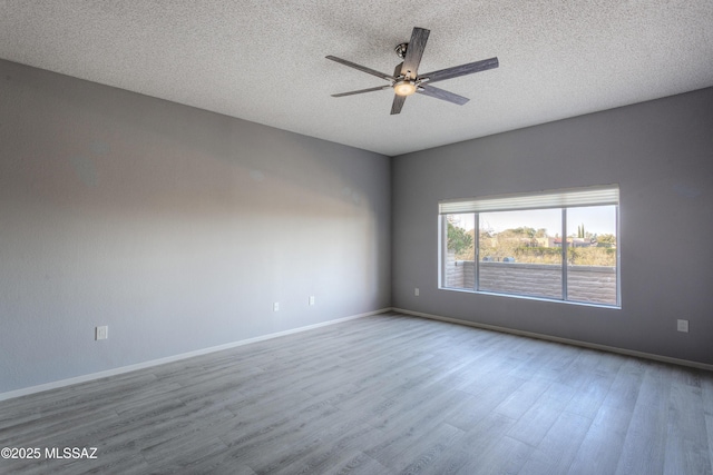 unfurnished room featuring baseboards, a textured ceiling, and wood finished floors