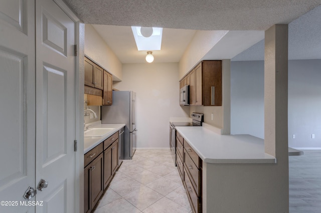 kitchen with a sink, stainless steel appliances, baseboards, and light countertops