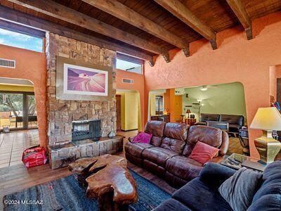 living room with visible vents, beam ceiling, a stone fireplace, and wooden ceiling