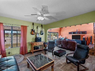 living area with a wealth of natural light, a textured ceiling, wood finished floors, and a ceiling fan