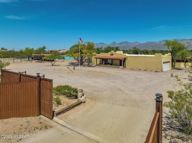 view of yard featuring a mountain view, a garage, dirt driveway, and fence