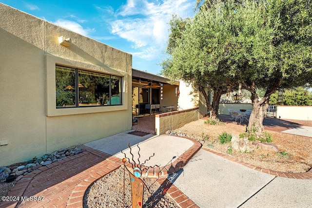 exterior space with stucco siding, a patio, and a ceiling fan