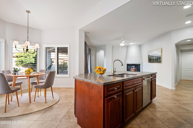 kitchen featuring stainless steel dishwasher, a fireplace, arched walkways, and a sink