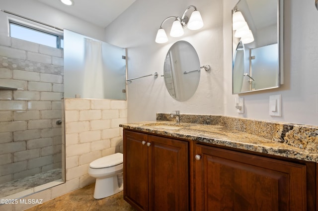 bathroom featuring vanity, toilet, and tiled shower