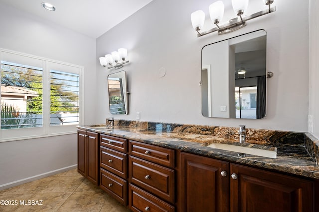 bathroom with a sink, baseboards, double vanity, and tile patterned flooring