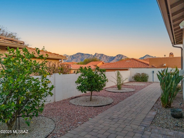 patio terrace at dusk featuring a mountain view and a fenced backyard