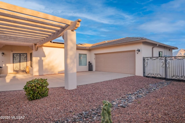 exterior space featuring stucco siding, a pergola, fence, concrete driveway, and a garage