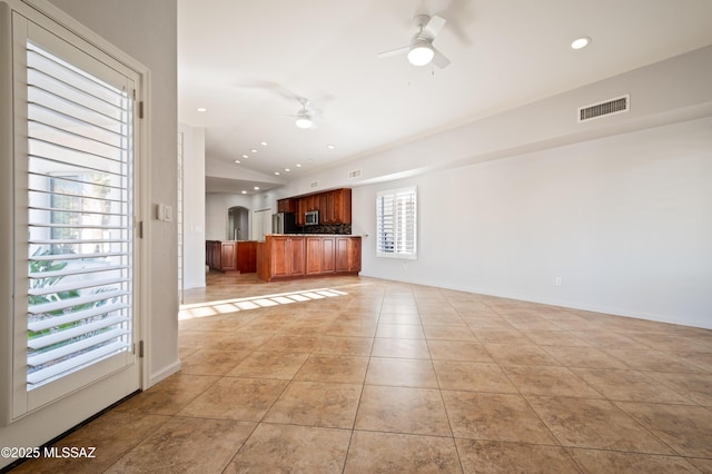 unfurnished living room featuring light tile patterned floors, visible vents, arched walkways, ceiling fan, and vaulted ceiling