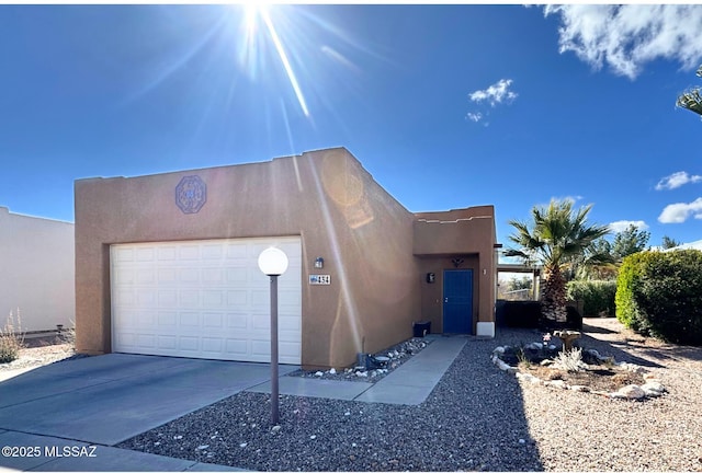 adobe home featuring stucco siding, driveway, and an attached garage