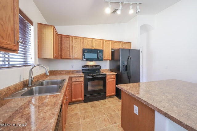 kitchen featuring black appliances, track lighting, a sink, brown cabinetry, and vaulted ceiling