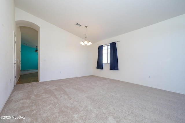 carpeted spare room with arched walkways, a notable chandelier, visible vents, and vaulted ceiling