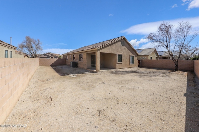 rear view of property featuring a patio, central AC unit, a fenced backyard, stucco siding, and a tiled roof