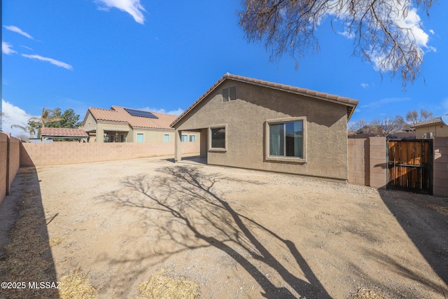 back of house featuring stucco siding, a gate, a fenced backyard, a patio area, and a tiled roof