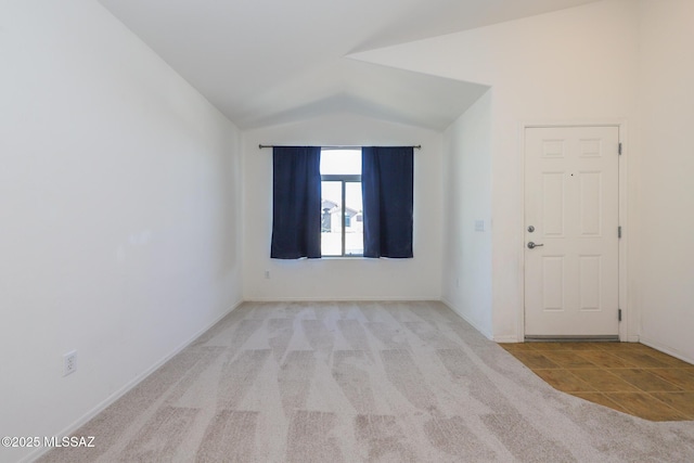 carpeted empty room with baseboards and lofted ceiling