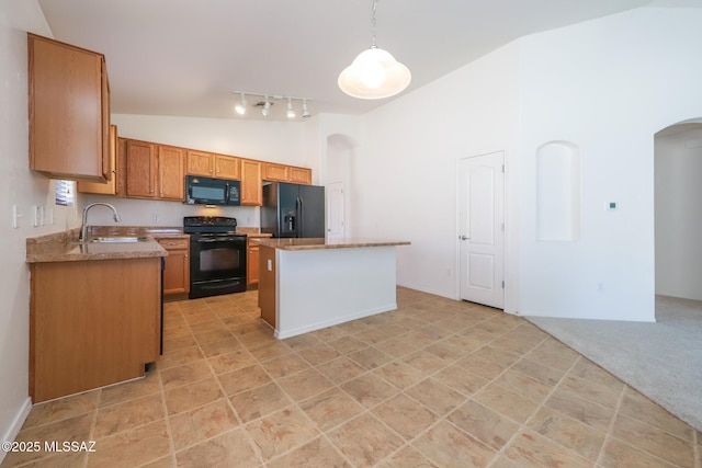 kitchen with black appliances, a sink, a kitchen island, arched walkways, and hanging light fixtures