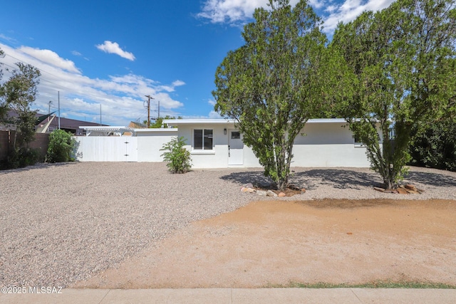 view of front of property featuring a gate, stucco siding, driveway, and fence