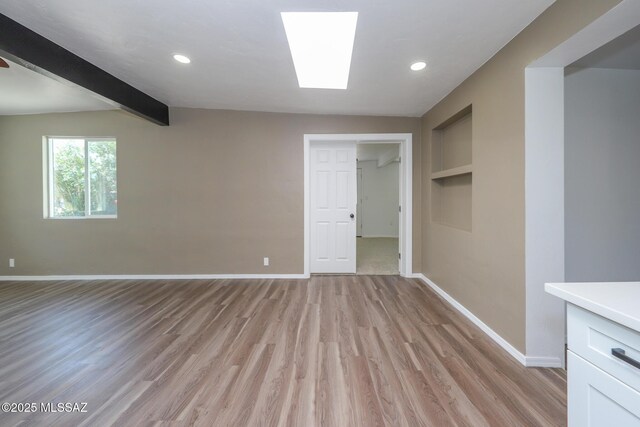 spare room with built in features, baseboards, light wood finished floors, recessed lighting, and beamed ceiling