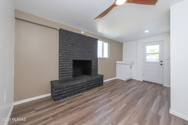 unfurnished living room featuring baseboards, a healthy amount of sunlight, wood finished floors, and a fireplace