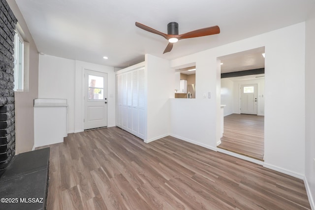 unfurnished living room featuring baseboards, wood finished floors, and a ceiling fan