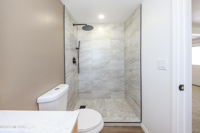 bathroom with tiled shower, toilet, vanity, and wood finished floors