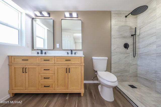 full bath with a tile shower, toilet, and a sink