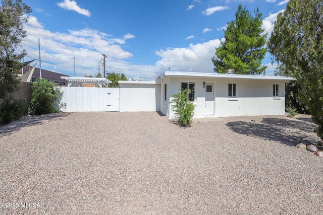 view of front of property featuring a gate, stucco siding, and fence