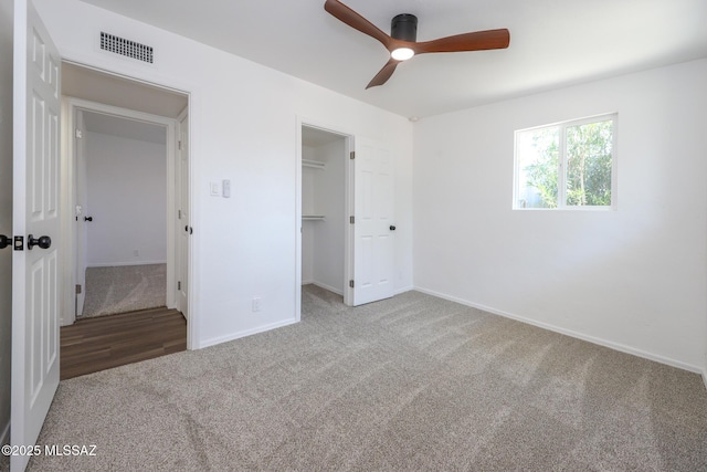 unfurnished bedroom with visible vents, a walk in closet, baseboards, carpet flooring, and a closet