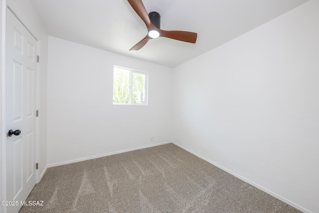 carpeted spare room with a ceiling fan and baseboards