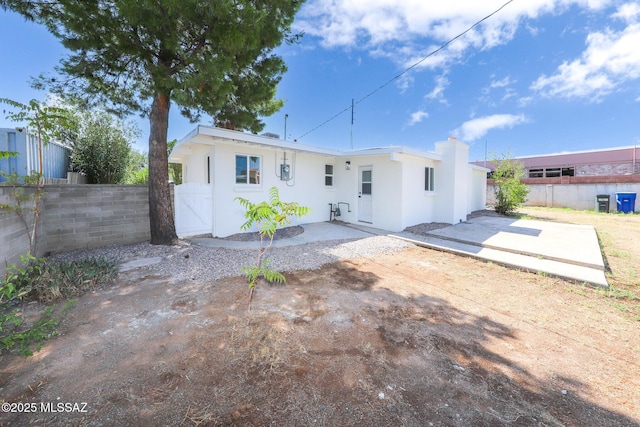 rear view of property featuring a patio area, fence, and stucco siding