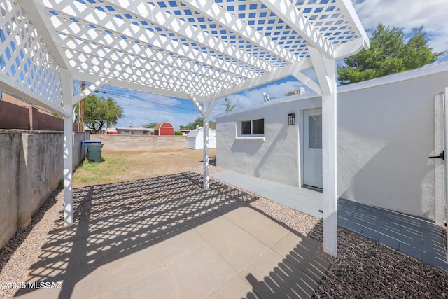 view of patio / terrace featuring a shed, a pergola, an outdoor structure, and fence