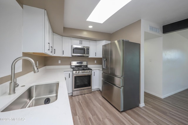 kitchen with visible vents, a skylight, a sink, appliances with stainless steel finishes, and light wood-type flooring