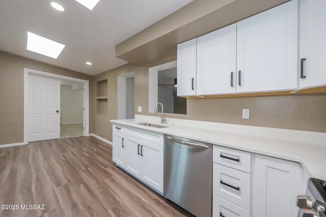 kitchen featuring a sink, stainless steel dishwasher, light wood-style floors, white cabinets, and light countertops